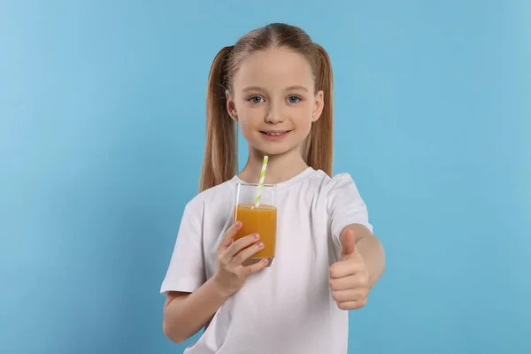 Cute Little Girl Świeżym Sokiem Pokazując Kciuki Górę Jasnoniebieskim Tle — Zdjęcie stockowe