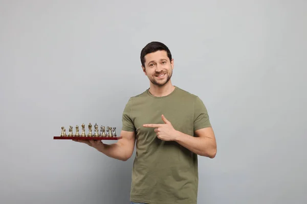 Όμορφος Άνθρωπος Δείχνει Σκακιέρα Κομμάτια Του Παιχνιδιού Ανοιχτό Γκρι Φόντο — Φωτογραφία Αρχείου