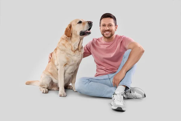 ライトグレーの背景に愛らしいラブラドールレトリバー犬と抱き合っている男 可愛いペット — ストック写真