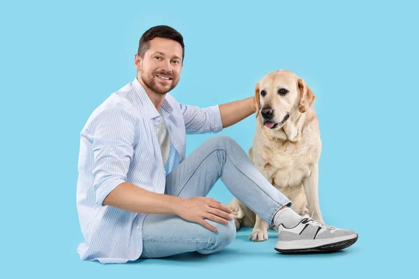 愛らしいラブラドールを持つ男ライトブルーの背景に犬を取得します 可愛いペット — ストック写真