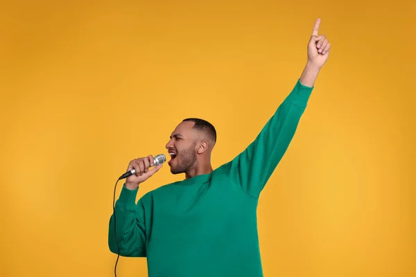 Mikrofonlu Yakışıklı Adam Turuncu Arka Planda Şarkı Söylüyor — Stok fotoğraf