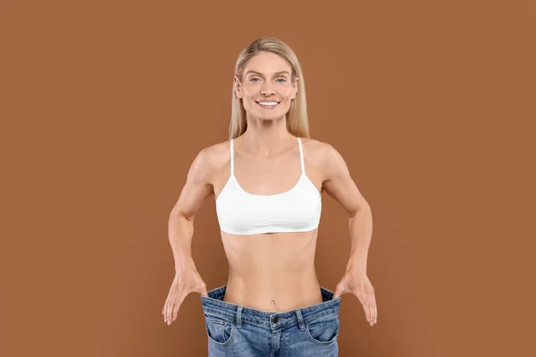 Schlanke Frau Großen Jeans Auf Braunem Hintergrund Gewichtsverlust — Stockfoto