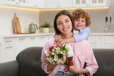 Küçük oğlu annesini Anneler Günü 'nde tebrik ediyor, mesaj için yer var. Bir buket güzel çiçek tutan bir kadın.
