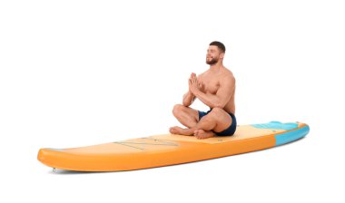 Beyaz arka planda turuncu SUP tahtasında yoga yapan mutlu bir adam.