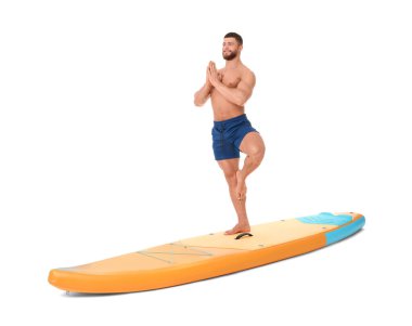 Beyaz arka planda turuncu SUP tahtasında yoga yapan mutlu bir adam.