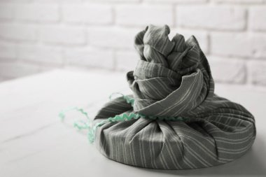 Furoshiki. Eşyalar beyaz mermer masa üzerinde kumaş içinde paketlenmiş, metin için boşluk