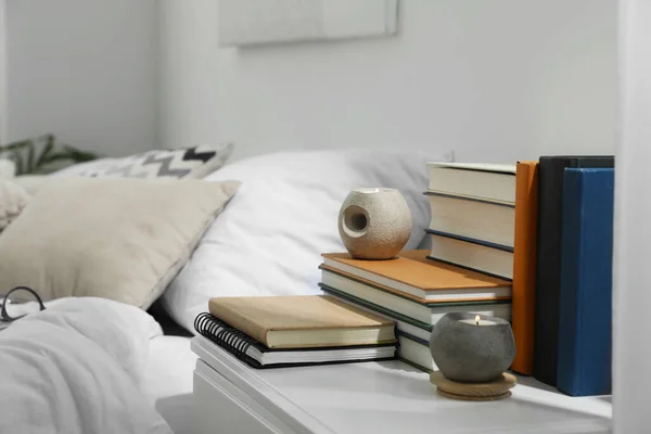 卧室白色床头柜上的精装书和香烛 — 图库照片