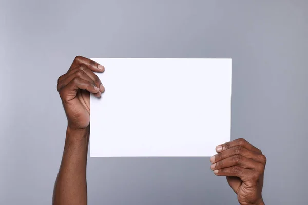 African American Man Holding Sheet Paper Grey Background Closeup Mockup — Stok fotoğraf
