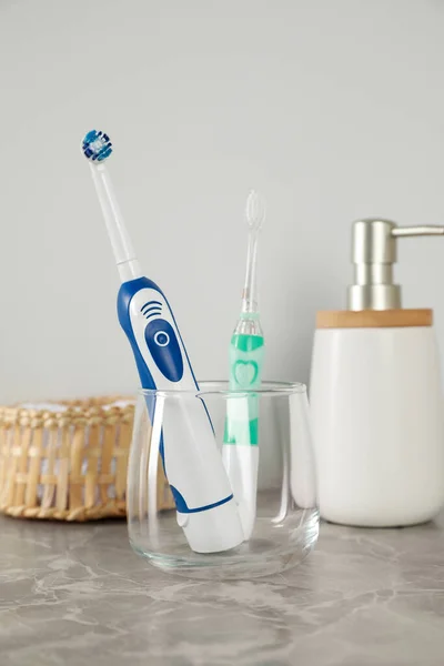 Electric Toothbrushes Glass Toiletries Light Grey Marble Table — Stock Photo, Image
