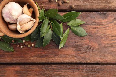 Aromatik defne yaprakları ve baharatlar ahşap masada, düz yerde. Metin için boşluk