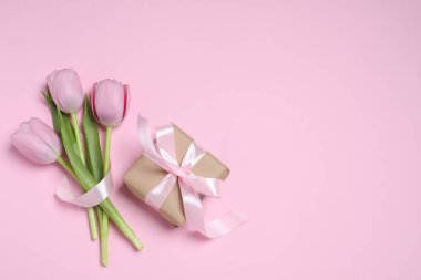 Pembe arka planda fiyonklu ve laleli güzel bir hediye kutusu var. Metin için boşluk