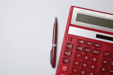 Açık gri arkaplan üzerinde hesap makinesi ve kalem, metin için boşluk ile düz uzanır