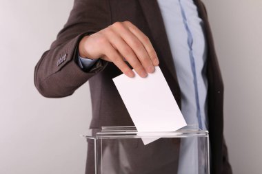 Adam oyunu açık gri arka planda sandığa koyuyor, yakın plan.