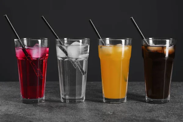 氷のキューブとグレーのテーブルの上にストローと異なるさわやかなソーダ水のメガネ — ストック写真