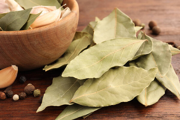 Ароматические лавровые листья и специи на деревянном столе, крупный план