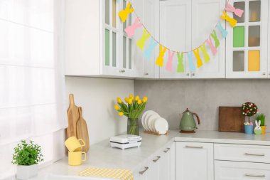 Renkli Paskalya dekoru ve sarı laleler mutfakta.