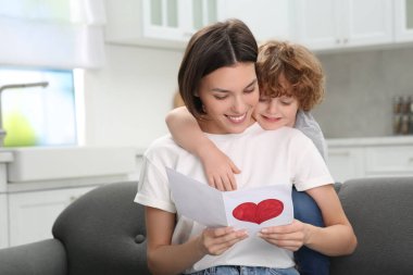 Anneler Günü 'nde annesini tebrik eden küçük bir çocuk. Elinde tebrik kartı tutan kadın.