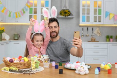 Baba ve tatlı kızı mutfaktaki masada selfie çekiyorlar. Paskalya yumurtaları boyuyorum.