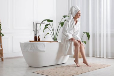 Güzel genç bir kadın banyoda pürüzsüz bacaklarına dokunuyor, mesaj için yer var.