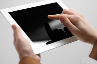 Açık gri arka planda modern tablet kullanan kadının yakın görüntüsü