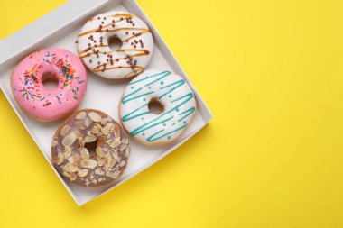 Sarı arka planda lezzetli jöleli çöreklerle dolu bir kutu. Metin için boşluk