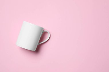 Pembe arka planda beyaz seramik bardak, üst manzara. Metin için boşluk