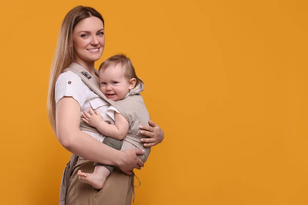 Mãe Segurando Seu Filho Funda Carrinho Bebê Fundo Laranja Espaço — Fotografia de Stock