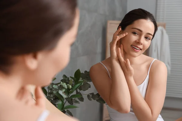 Jovem Mulher Massageando Seu Rosto Perto Espelho Banheiro — Fotografia de Stock