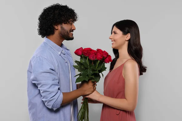 国際的なデート 幸せなカップルともにバラの花束のライトグレーの背景 — ストック写真