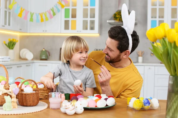 爸爸和他可爱的儿子在厨房里画复活节彩蛋的时候玩得很开心 — 图库照片