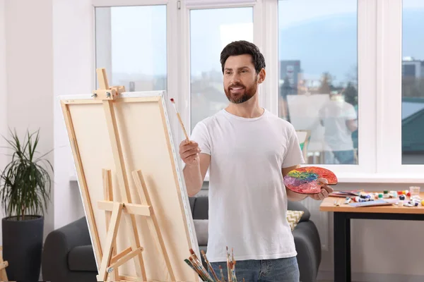 スタジオで絵を描く男 キャンバスを保持するためにイーゼルを使用 — ストック写真