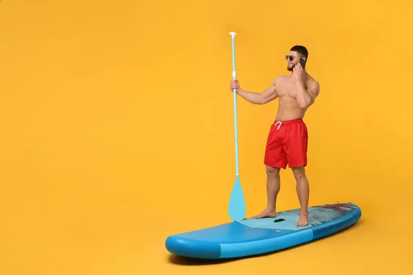 Ευτυχισμένος Άνθρωπος Κουπί Μιλάμε Για Smartphone Στο Sup Σκάφους Πορτοκαλί — Φωτογραφία Αρχείου