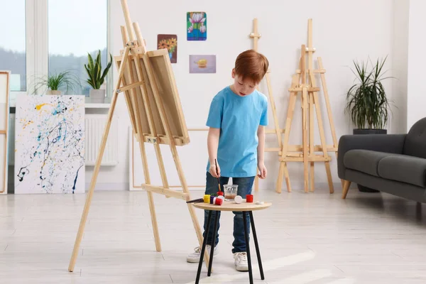スタジオで絵を描く少年 キャンバスを保持するためにイーゼルを使用 — ストック写真