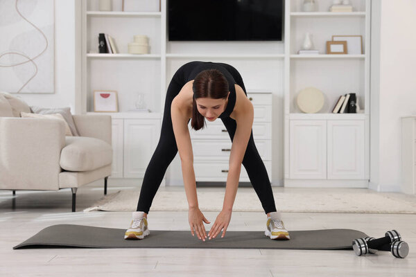 Morning routine. Sporty woman doing stretching exercise at home
