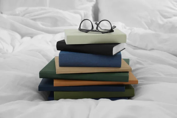 ハードカバー本と眼鏡上の白いベッド — ストック写真