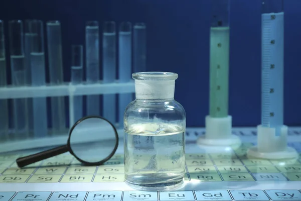 化学元素周期表上的放大镜和玻璃瓶 — 图库照片