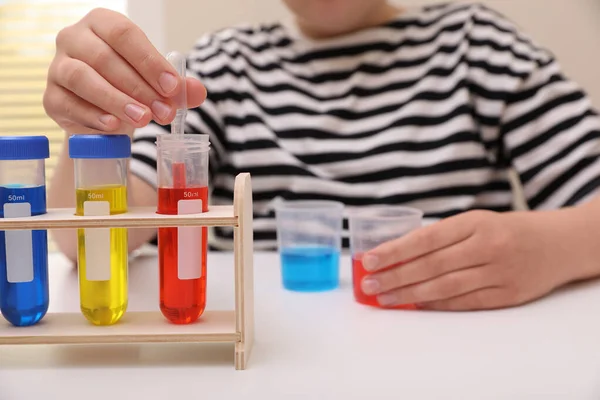 女孩将五颜六色的液体混合在室内的白桌上 选择焦点 儿童化学实验集 — 图库照片