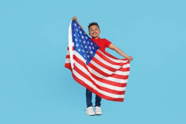 4 Temmuz - ABD 'nin Bağımsızlık Günü. Açık mavi arka planda Amerikan bayrağı taşıyan mutlu çocuk