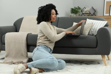 İçerde dizüstü bilgisayar kullanan mutlu genç bir kadın.