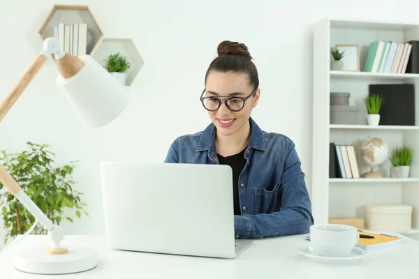 家庭工作场所快乐的女人在房间里的白色桌子边工作着笔记本电脑 — 图库照片