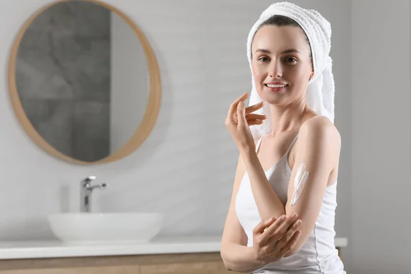 快乐的女人在浴室的胳膊上涂上护肤霜 留有文字的空间 — 图库照片