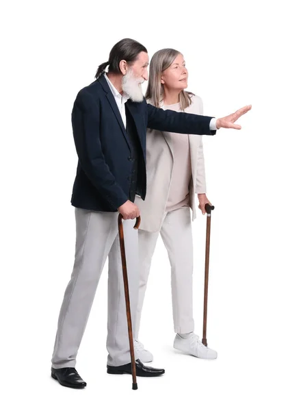 上了年纪的男人和女人拿着手杖看着白色背景的东西 — 图库照片