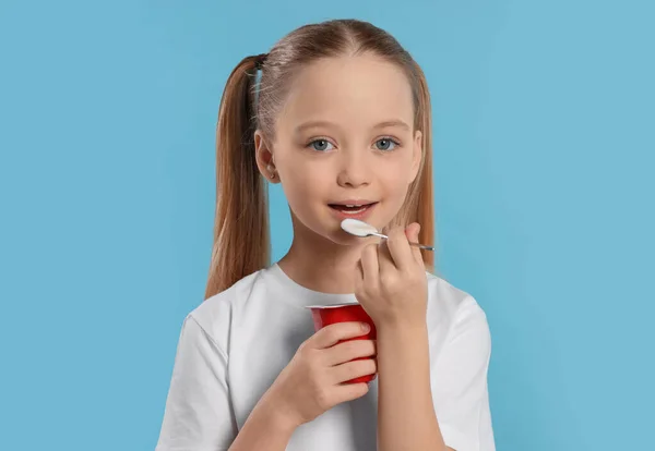 Menina Bonito Comer Iogurte Saboroso Fundo Azul Claro — Fotografia de Stock