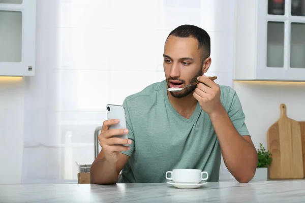 Mladý Muž Používá Smartphone Při Snídani Bílého Mramorového Stolu Kuchyni — Stock fotografie