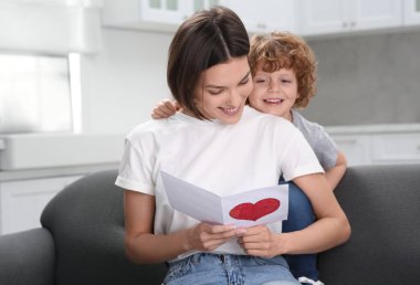 Anneler Günü 'nde annesini tebrik eden küçük bir çocuk. Elinde tebrik kartı tutan kadın.