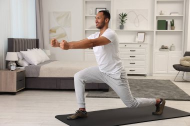 Adam evde spor paspası üzerinde sabah egzersizi yapıyor.