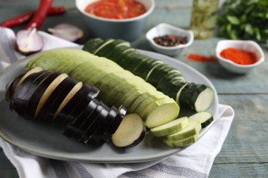 Lezzetli ratatouille pişiriyorum. Açık mavi ahşap masada taze kesilmiş sebzeli tabak, yakın plan.