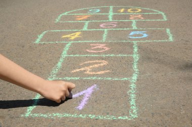 Çocuk asfaltta renkli tebeşirle seksek oynuyor, yakın plan.