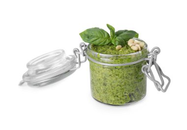 Lezzetli pesto sosu, çam fıstığı ve fesleğen yaprakları beyaz kavanozda izole edilmiş.