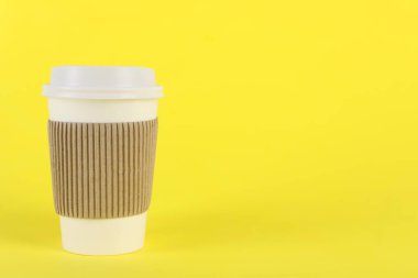 Sarı arka planda plastik kapaklı kağıt bardak, metin için boşluk. Kahve hazır.
